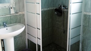 Een badkamer met een douche in hoek, een wastafel en een spiegel.