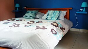 Een bed met een bloemenprint sprei, twee kussens en een houten hoofdbord.