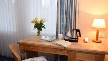 Ein Holztisch mit einer Vase gelber Blumen, einer Kaffeemaschine, einer Lampe und einem Buch.
