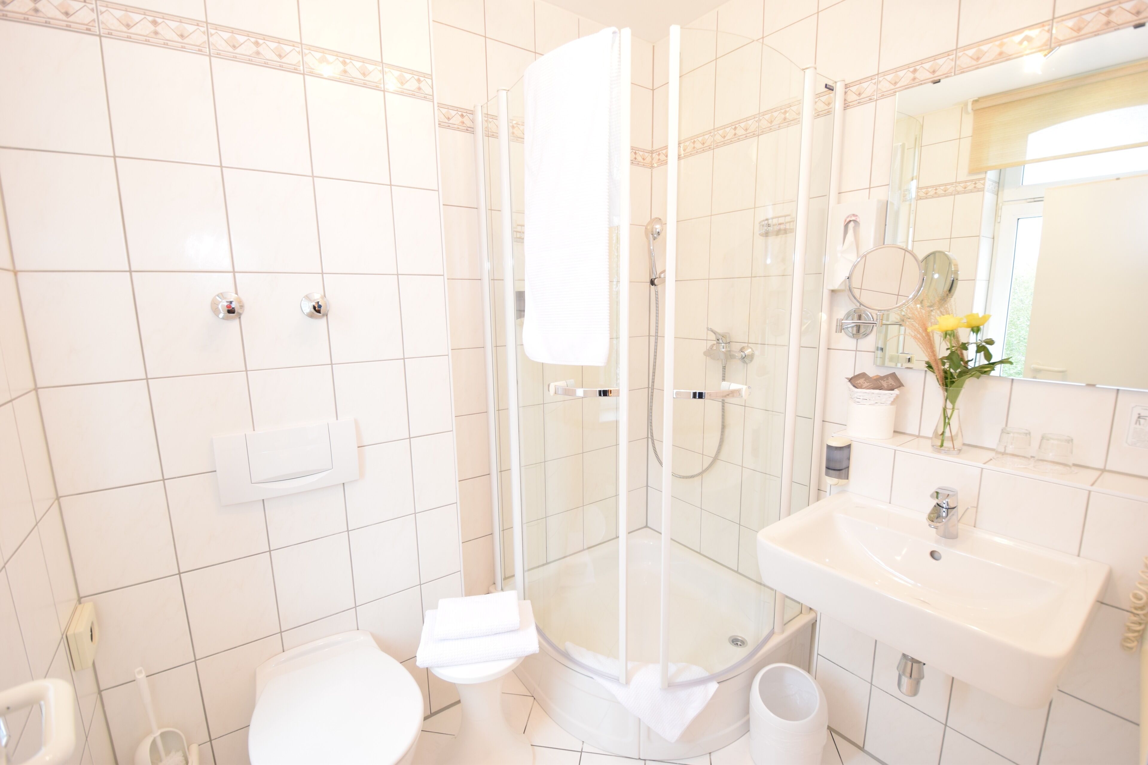 Un baño moderno con ducha acristalada, lavabo blanco y retrete.