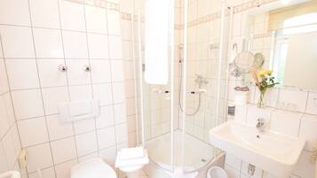 A modern bathroom with a glass-enclosed shower, a white sink, and a toilet.