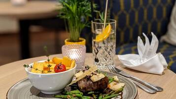 A dining table with a plate of food, a glass of water, and a small plant.