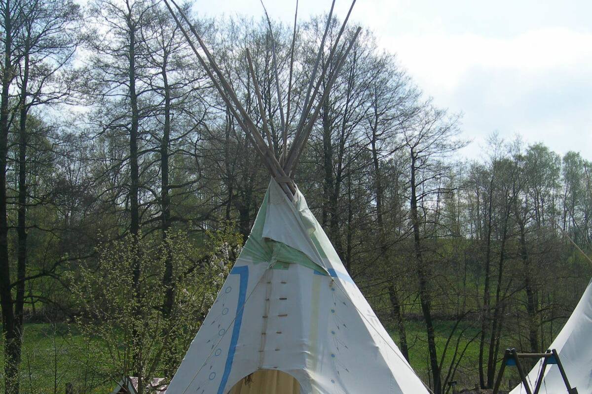 Ein Tipizelt mit schlichtem Eingang und einem kleinen Bauwerk in der Nähe.