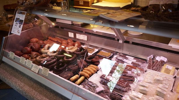 A deli counter with various meats and cheeses displayed in a glass case.