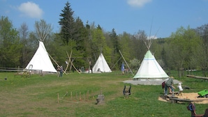 A campsite with several teepees, a playground, and a dirt path.