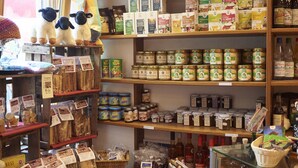 A store with shelves stocked with various food items, including bread, jars, and bottles.