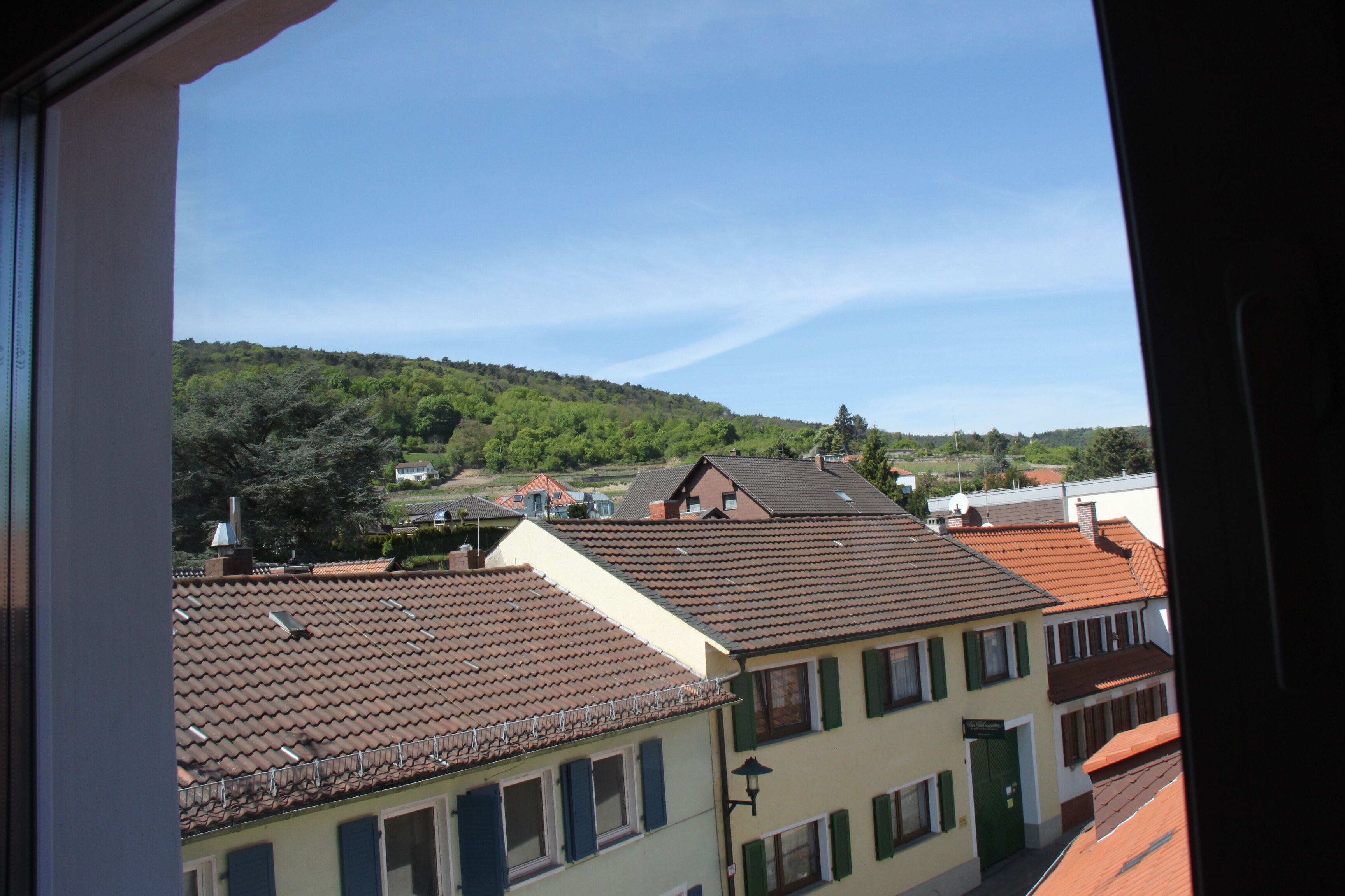 A view of a residential area with terraced houses, a hill in the background, and a clear sky.