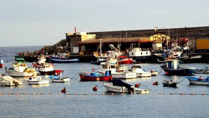 A harbor with multiple boats docked, a large building in the background, and a clear sky. - Playa San Juan, a large apartment with 3 bedrooms, for families, group  (Playa San Juan)