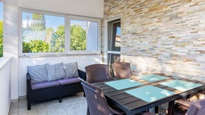 A sunlit patio with a stone wall, a cushioned bench, and a wooden table with blue placemats.