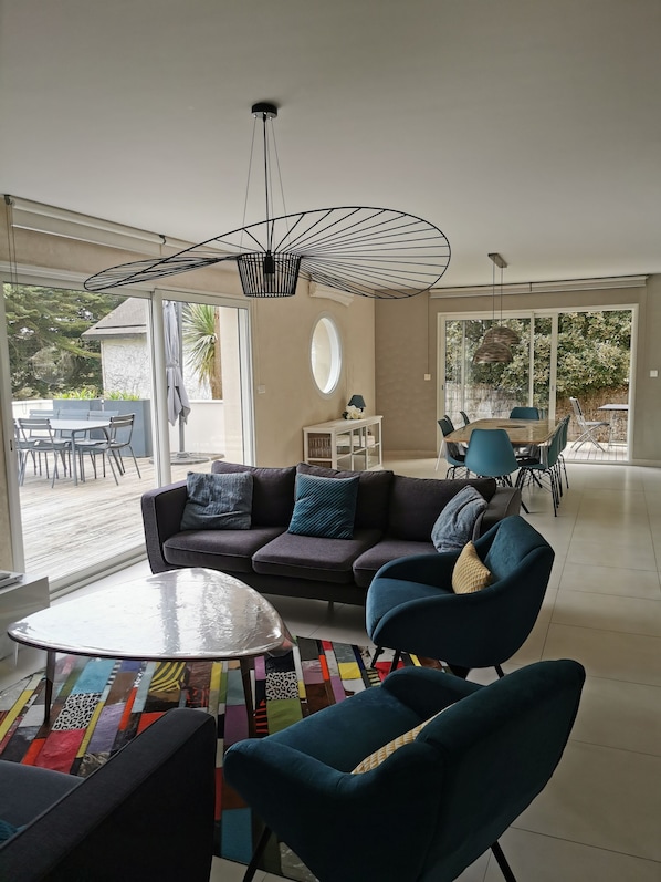 A modern living room with a sofa, chairs, a coffee table, and a dining area with a table and chairs.