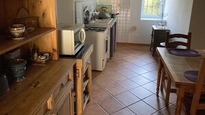 Cocina compacta con estufa, microondas y estantes de madera.