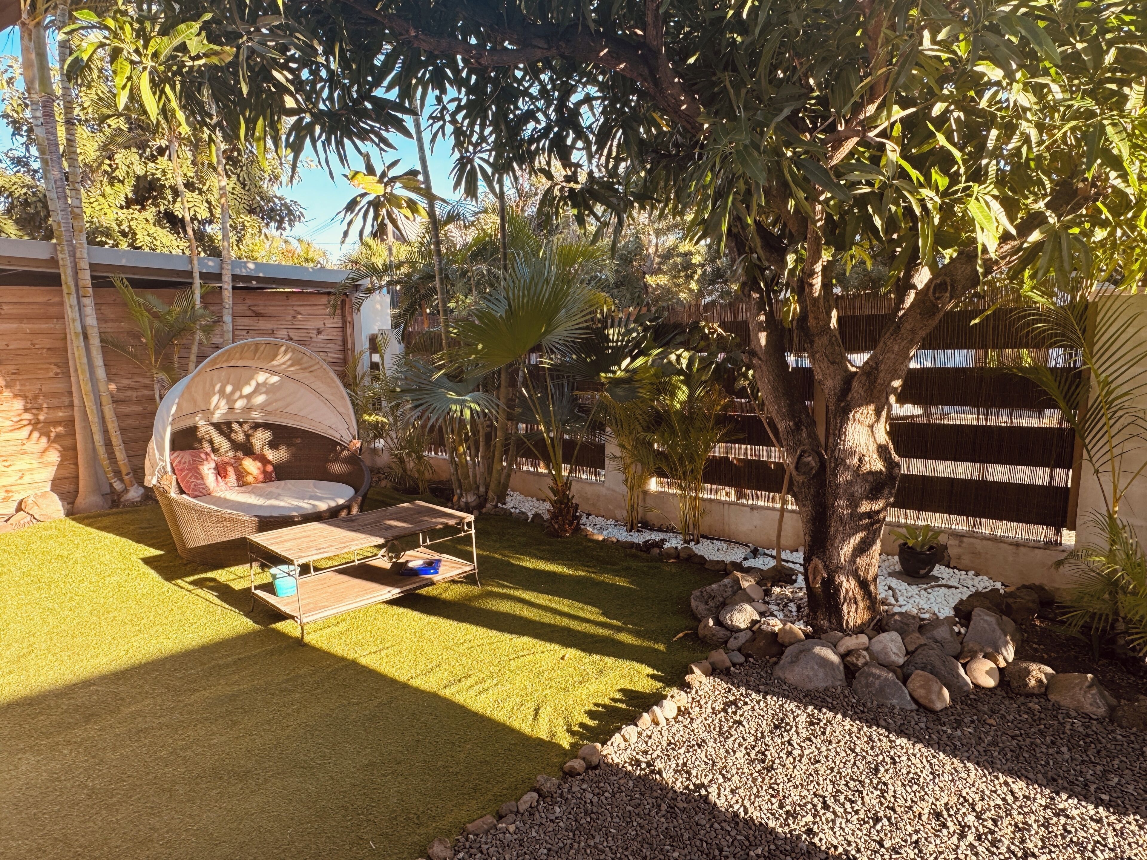 A garden with a hanging chair, a wooden deck, and a variety of plants.