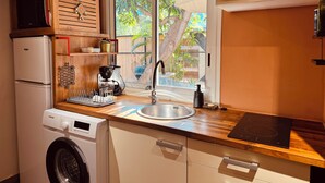 Een praktische keuken met een geïntegreerde wasmachine, een koffiezetapparaat en een spoelbak.