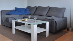 Una sala de estar moderna con un sofá gris, una mesa de centro blanca y una lámpara de pie.