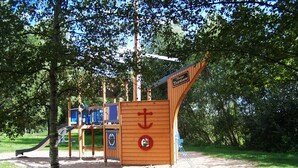 Un parque infantil con tobogán, estructuras para escalar y una casita de madera.