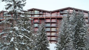 Un edificio de varios pisos con balcones, rodeado de árboles cubiertos de nieve.