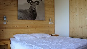 Un dormitorio con cabecera de madera, cama con ropa de cama blanca y un cuadro de un ciervo colgado en la pared.