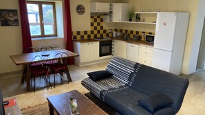 A compact living space with a dining area, kitchenette, and a sofa.