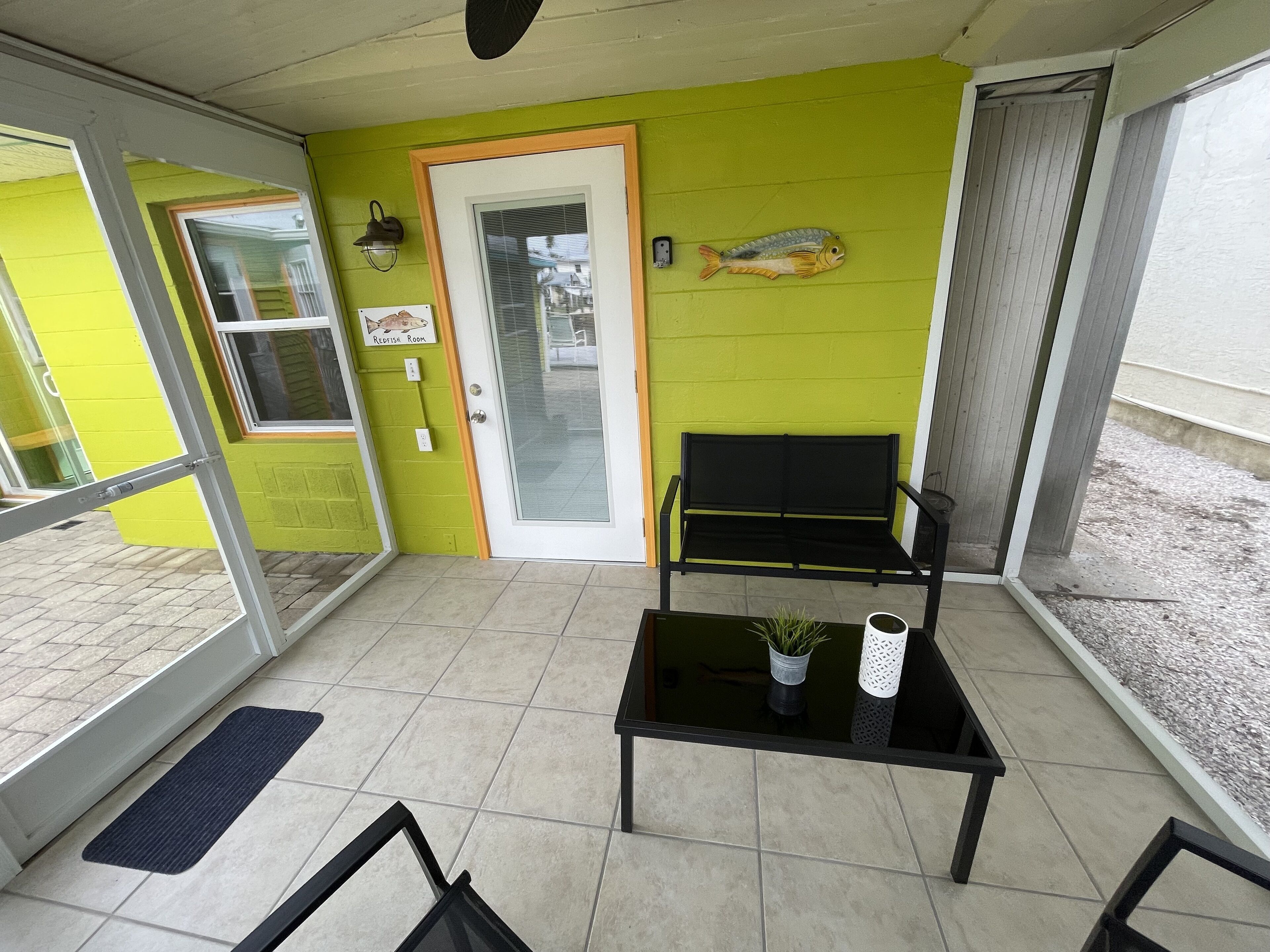 A room with a green wall, a black bench, a small table with a plant, and a fish decoration.