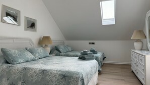 Un dormitorio con dos camas, un aparador, una ventana y dos lámparas fijadas a la pared.