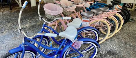 Una hilera de bicicletas con asientos para niños estacionadas sobre una superficie de grava.