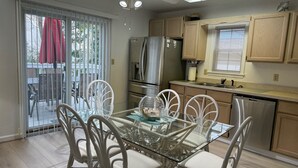 Una cocina moderna con armarios blancos, un refrigerador de acero inoxidable y un lavavajillas.