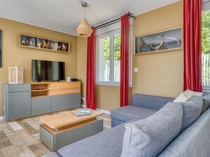 Ein modernes Wohnzimmer mit einer Couch, einem Couchtisch, einem Fernseher und einem Bücherregal.