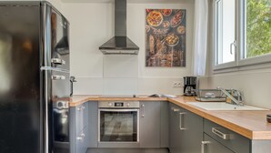 A modern kitchen with stainless steel appliances, a wooden countertop, and a large window.