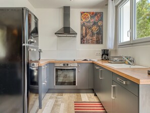 Eine moderne Küche mit Edelstahlgeräten, einer Holz Arbeitsplatte und einem großen Fenster.