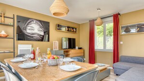 A dining area with a wooden table, chairs, and a TV.