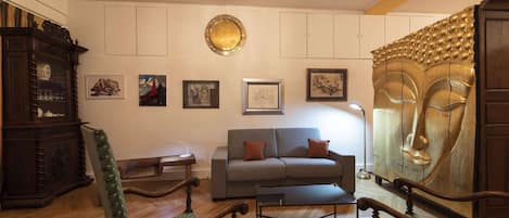 Una sala de estar con sofá, dos sillones, un aparador de madera y una araña.