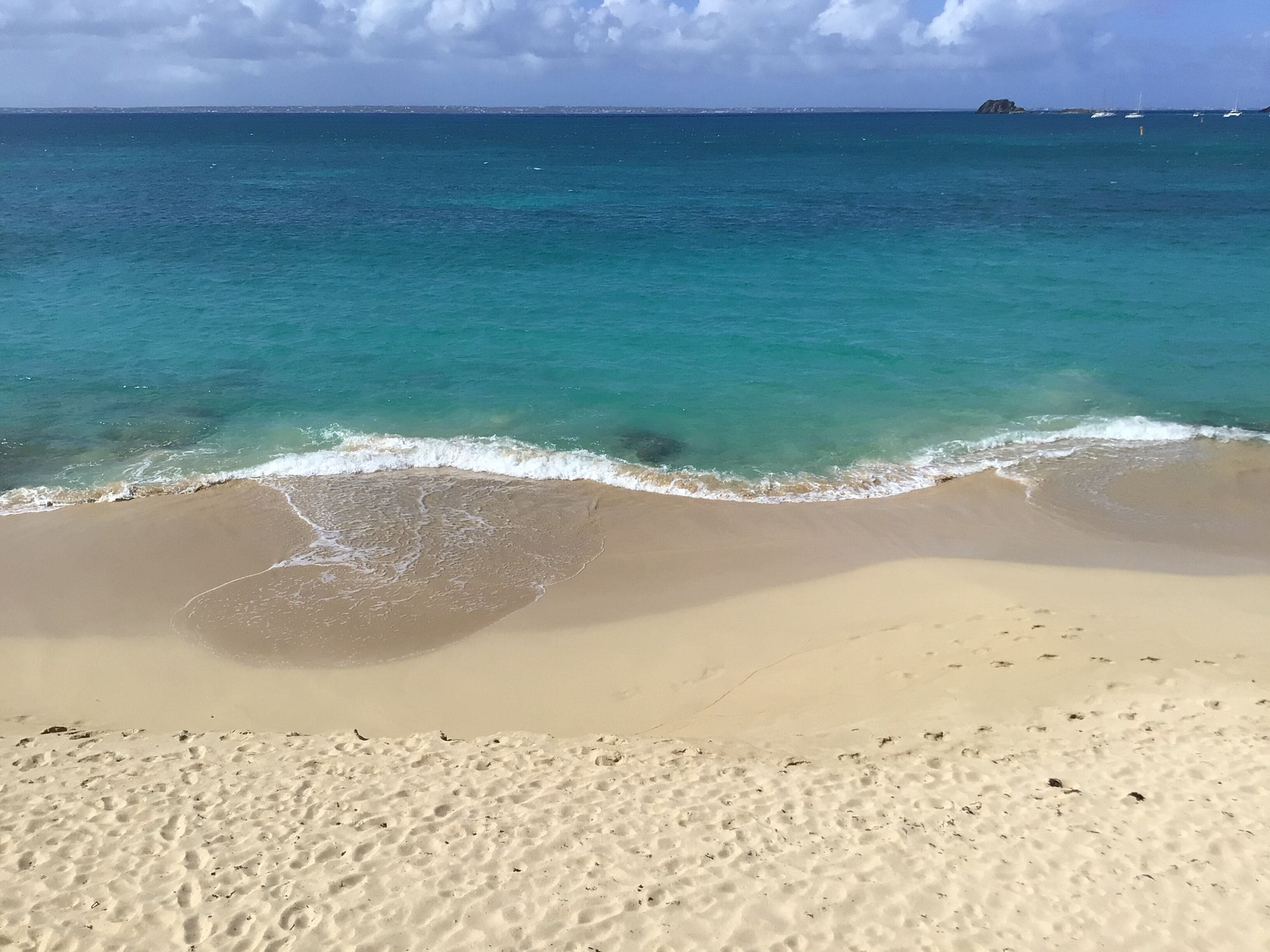 A beach with clear turquoise water and a sandy shore.