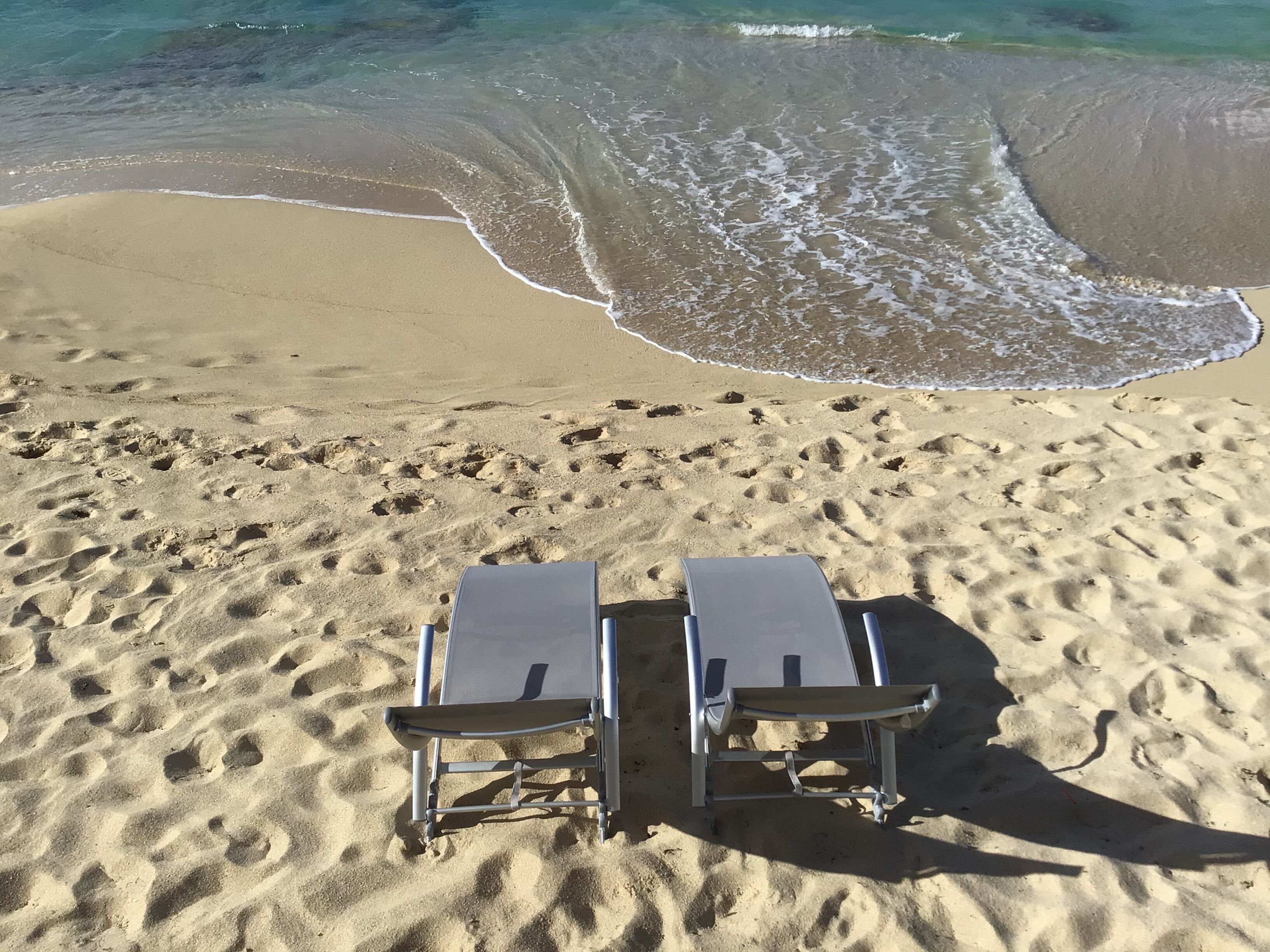 Una platja amb dues gandules mirant l'oceà.