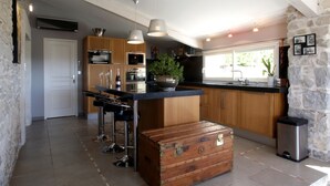 A modern kitchen with a central island, bar stools, and a vintage trunk.