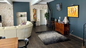 A living room with a stone wall, a white sofa, a wooden coffee table, a fireplace, and a staircase.
