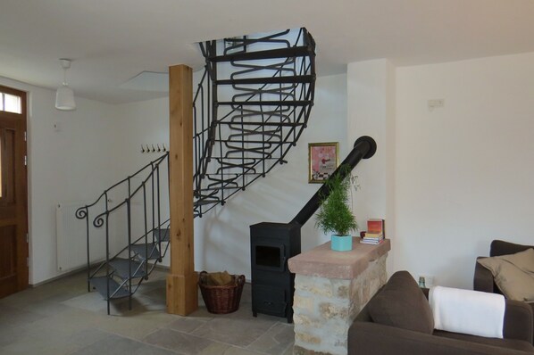 Una escalera de diseño espiral, una chimenea, un sofá y una planta colgante.