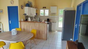 A kitchen with a wooden island, yellow chairs, and a blue door. - house 4/5 pers near lake and ocean (HOURTIN)