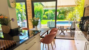 Cozinha moderna com área de jantar, grandes janelas e vista para o jardim e piscina.