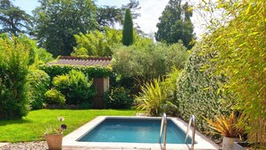 Uma piscina com um deck ao redor, espreguiçadeiras e uma pequena mesa.