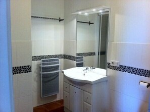 Une salle de bain avec un lavabo blanc, un miroir et un porte-serviettes.