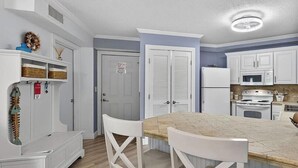 Une cuisine avec des meubles blancs, un plan de travail en bois et un coin repas blanc avec deux chaises.
