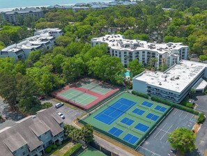 Ein mehrstöckiges Gebäude mit Pool und Tennisplätzen auf dem Dach.