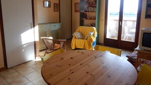 Une pièce chaleureuse avec une table en bois, une chaise jaune et une bibliothèque.