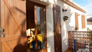 Une porte en bois qui donne sur une pièce d’où l’on peut apercevoir une personne vêtue d’une combinaison jaune.