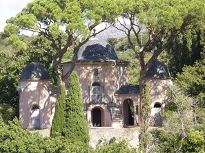 Un bâtiment historique doté d’un dôme central et de deux dômes plus petits, le tout entouré d’arbres.