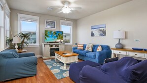 Un salon avec un canapé bleu, une table basse en bois et un ventilateur de plafond.
