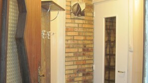 A hallway with a brick wall, a white door with a glass panel, and a wooden door frame.