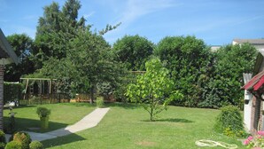 A well-maintained garden with a clear pathway, a small tree, and various shrubs.