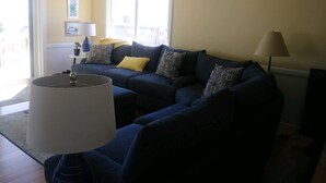 Un salon avec un canapé bleu foncé, une lampe et une fenêtre donnant sur un beau paysage.