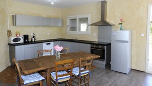 Une cuisine compacte comprenant une table à manger, des chaises, un réfrigérateur, une cuisinière et un four à micro-ondes.